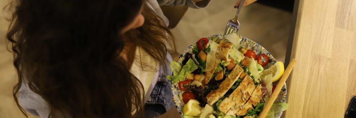 Overhead view of a woman eating a chicken salad balancing health with deliciousness.