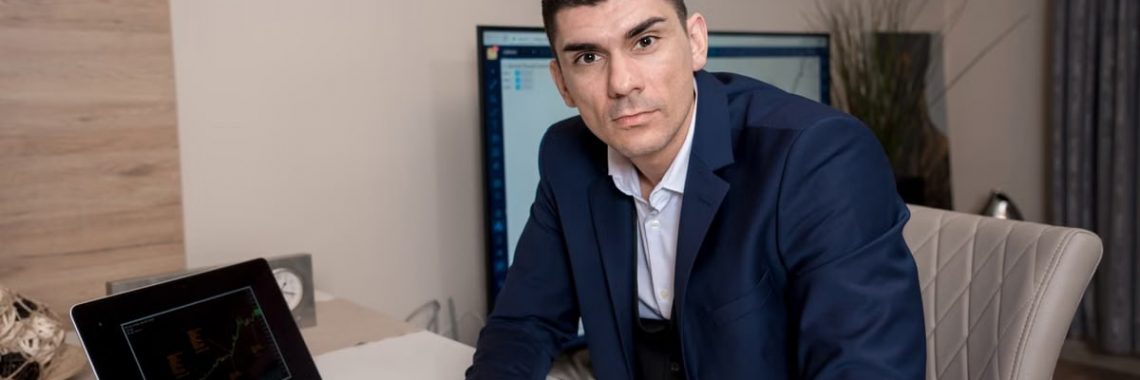 Businessman in blue suit working on laptop in sleek office setting, conveying professionalism and focus.